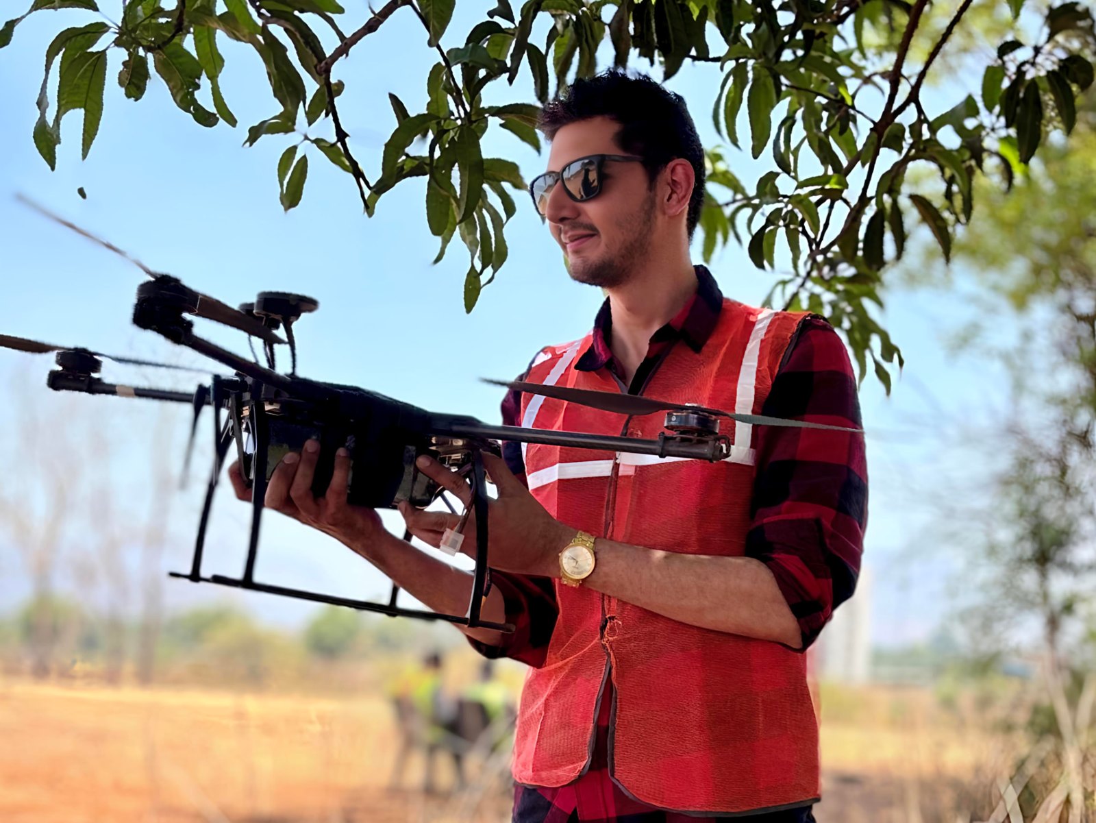 Vinay Dambani holding a large training drone while wearing a red high-visibility safety vest